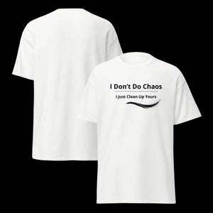 Op de afbeelding: Een wit T-shirt met korte mouwen en de zwarte tekst I Don't Do Chaos I Just Clean Up Yours met een decoratieve zwarte zwaai-afbeelding eronder. Het T-shirt wordt getoond vanuit zowel de voor- als achterkant tegen een zwarte achtergrond.