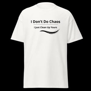 Op de afbeelding: Een wit T-shirt met korte mouwen en de zwarte gedrukte tekst I Don't Do Chaos I Just Clean Up Yours, geplaatst boven een zwarte gebogen grafische lijn met een klein gespikkeld ontwerp aan het uiteinde, gecentreerd op de borst.