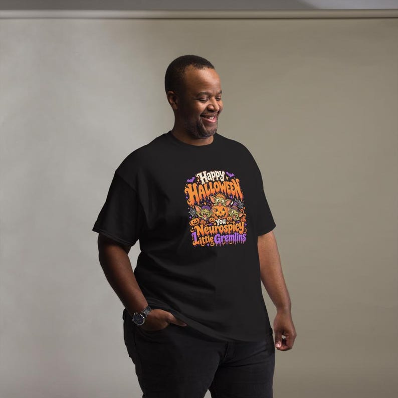 May include: A black short-sleeve t-shirt featuring a colorful graphic print that reads Happy Halloween You Neurospicy Little Gremlins. The design includes illustrations of small green creatures, orange pumpkins, purple bats, and stars.