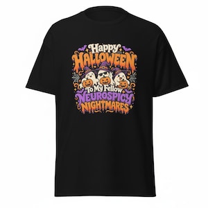 May include: A black short-sleeve t-shirt featuring a graphic print with three ghosts wearing purple witch hats and holding orange jack-o'-lanterns. The text reads Happy Halloween To My Fellow Neurospicy Nightmares in orange and purple lettering.