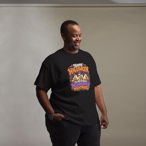 May include: A black short-sleeved t-shirt featuring a colourful graphic print with the text "Happy Halloween To My Fellow Neurospicy Nightmares." The design includes three ghosts wearing witch hats, orange pumpkins, purple bats, and stars.