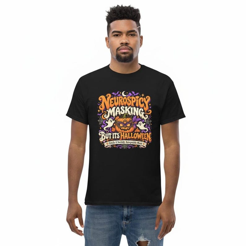 Pu&ograve; includere: Una t-shirt nera con una grafica colorata che riporta il testo "NEUROSPICY MASKING BUT ITS HALLOWEEN" e "Finally A Socially Acceptable Mask". Il disegno include una zucca con una maschera, due fantasmi e alcuni pipistrelli.