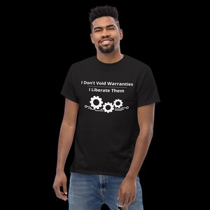 May include: A black short-sleeved t-shirt featuring white text that reads I Don't Void Warranties I Liberate Them above a graphic of three interconnected gears with circuit board lines extending from the sides of the gear assembly.