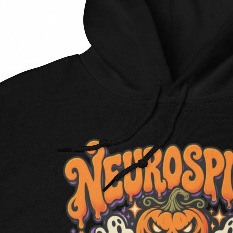 May include: A black hooded sweatshirt featuring a graphic print with the orange text Neurospicy in a dripping font style, accompanied by a jack-o'-lantern pumpkin, small white ghosts, and orange star accents on the front chest area.