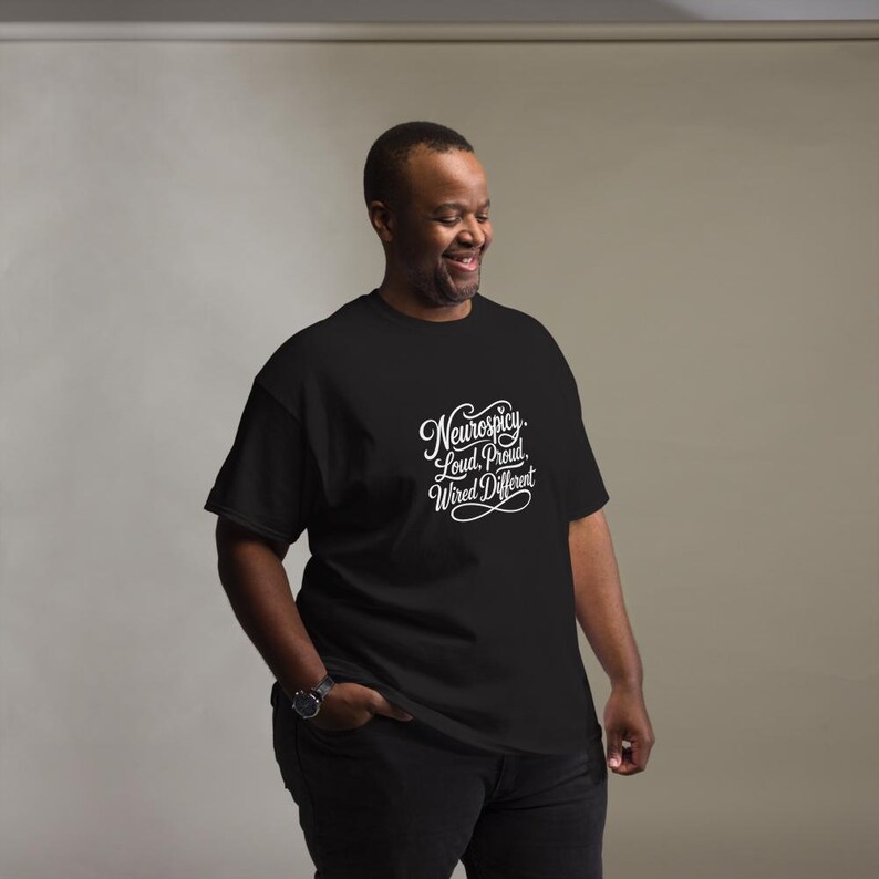 K&ouml;nnte beinhalten: Ein schwarzes T-Shirt mit kurzen &Auml;rmeln und wei&szlig;em, kursivem Text auf der Brust, der Neurospicy, Loud, Proud, Wired Different lautet. Das T-Shirt hat einen Rundhalsausschnitt und eine Standardpassform f&uuml;r einen klaren, gut lesbaren Look.