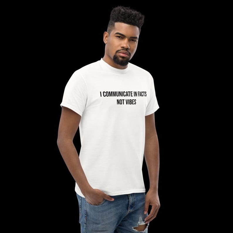 Peut inclure: Un t-shirt blanc &agrave; manches courtes avec le texte noir "I COMMUNICATE IN FACTS NOT VIBES" imprim&eacute; sur la poitrine. Le v&ecirc;tement pr&eacute;sente un col rond et une coupe standard, associ&eacute; &agrave; un jean bleu en denim avec un d&eacute;tail us&eacute; au niveau du genou.