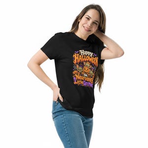 May include: A black short-sleeved t-shirt featuring a colorful Halloween graphic with orange, purple, and green accents. The design includes cartoon creatures, pumpkins, and the text: Happy Halloween You Neurospicy Little Gremlins.