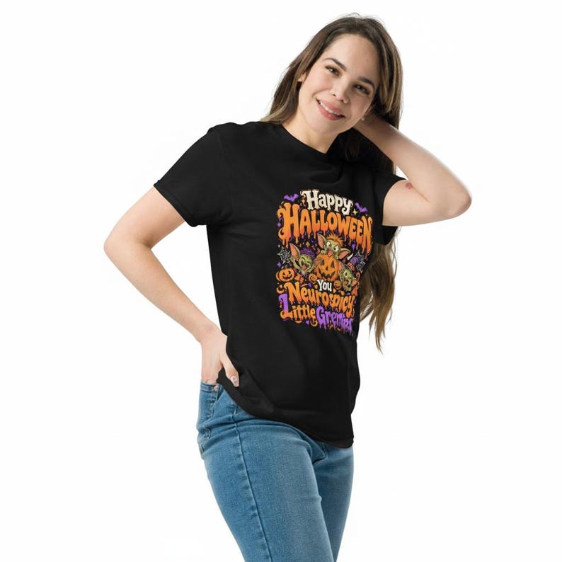May include: A black short-sleeved t-shirt featuring a colorful Halloween graphic with orange, purple, and green accents. The design includes cartoon creatures, pumpkins, and the text: Happy Halloween You Neurospicy Little Gremlins.