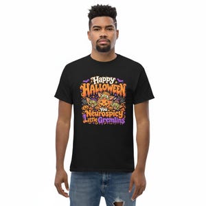 May include: A black t-shirt featuring a colorful Halloween graphic with three green creatures and pumpkins. The text reads Happy Halloween You Neurospicy Little Gremlins in orange and purple lettering, surrounded by bats and spider web accents.