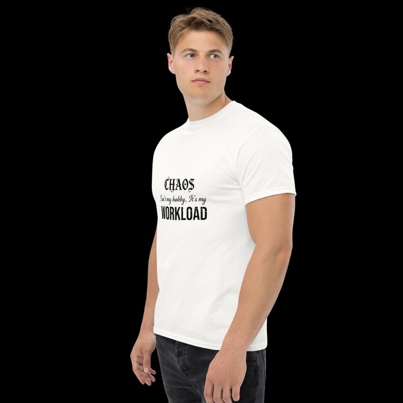 May include: A white short-sleeved t-shirt featuring black text on the chest that reads: CHAOS isn't my hobby, It's my WORKLOAD. The shirt has a crew neckline and a standard fit, presented against a plain black background for clear visibility.