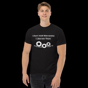 May include: A black short-sleeved t-shirt featuring white text that reads I Don't Void Warranties I Liberate Them, positioned above a graphic of three interconnected gears and circuit board lines centred on the chest of the garment.