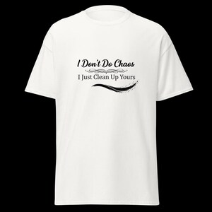 Puede incluir: Una camiseta blanca de manga corta con texto negro impreso en el pecho que dice I Don't Do Chaos I Just Clean Up Yours, acompa&ntilde;ado de un adorno decorativo y un gr&aacute;fico de pincelada curva debajo del texto.