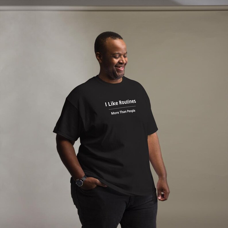 K&ouml;nnte beinhalten: Ein schwarzes kurz&auml;rmeliges T-Shirt mit wei&szlig;em Text, der I Like Routines lautet, gefolgt von einer horizontalen Linie und dem Text More Than People. Das T-Shirt hat einen Rundhalsausschnitt und eine Standardpassform f&uuml;r ein schlichtes Design.
