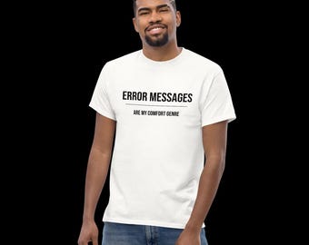 May include: A white short-sleeved t-shirt featuring the black text ERROR MESSAGES centered on the chest, with a horizontal line underneath and the text ARE MY COMFORT GENRE positioned below the line in a smaller black sans-serif font.