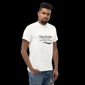 Puede incluir: Una camiseta blanca de manga corta con texto negro que dice I Don't Do Chaos I Just Clean Up Yours, con adornos decorativos encima y debajo del texto. La camiseta se lleva con unos vaqueros azules de mezclilla con un detalle desgastado.