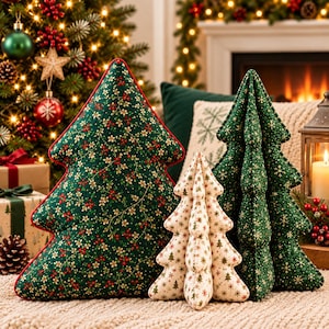 May include: Three fabric Christmas tree decorations in varying sizes. One large tree features a dark green fabric with a floral and berry pattern. A medium tree is dark green with gold snowflakes. A small tree is cream with small green trees.