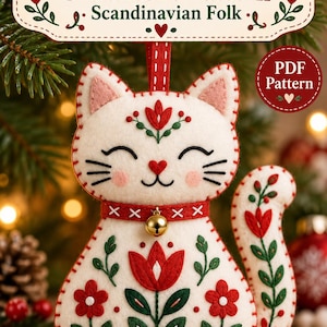 Puede incluir: Un adorno de gato de fieltro blanco con bordados florales rojos y verdes, un collar rojo con un pequeño cascabel dorado y bordes cosidos. La etiqueta superior dice Felt Cat Ornament Pattern Scandinavian Folk, con un sello de PDF Pattern.