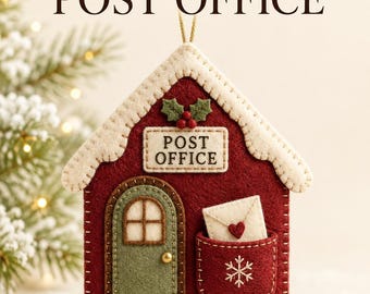 May include: A felt ornament shaped like a house with the text "WOODLAND CHRISTMAS POST OFFICE" and "POST OFFICE" on the building. It features a red exterior, a green door, a white roof, and a pocket containing a small envelope with a red heart.