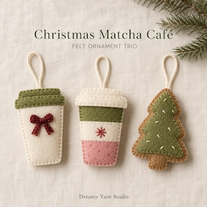 Op de afbeelding: Een trio van vilten ornamenten met twee koffiebekervormen en één kerstboomvorm. De eerste beker is crème met een groen deksel en een rode strik. De tweede beker heeft crème, groene en roze secties met een rood sterretje erop geborduurd.