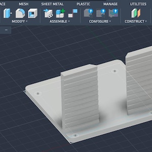 Pode incluir: Uma interface de software CAD 3D exibindo uma base retangular cinza claro com dois painéis retangulares verticais canelados. O painel do navegador à esquerda lista componentes, incluindo CampChairHolder, StickerTool e Bottle label.