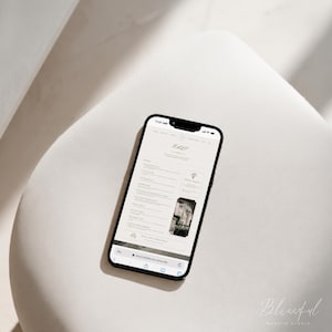 May include: A black smartphone displaying a website interface with the text "BELLE" at the top. The screen shows a list of menu options, a small square image of a bouquet, and a rectangular image of a building, all on a clean white background.