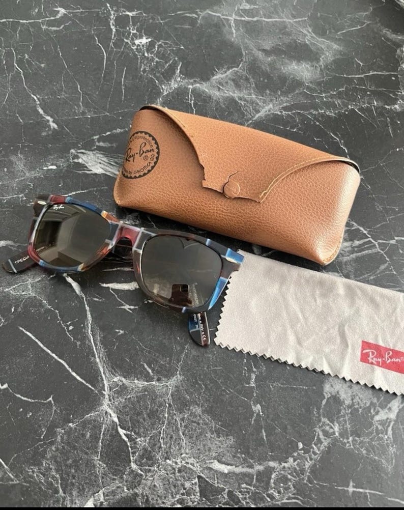 Puede incluir: Gafas de sol Ray-Ban con montura de carey multicolor con detalles en azul y marr&oacute;n, lentes oscuras, un estuche protector de cuero color canela con cierre de broche y un pa&ntilde;o de limpieza de microfibra gris claro con el logo de Ray-Ban.