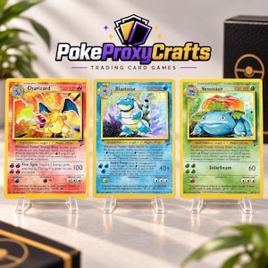 May include: Three rectangular trading cards featuring Charizard, Blastoise, and Venusaur displayed on clear plastic stands. Each card displays character artwork, HP values, and text descriptions. The logo PokeProxyCrafts Trading Card Games is visible above the cards.