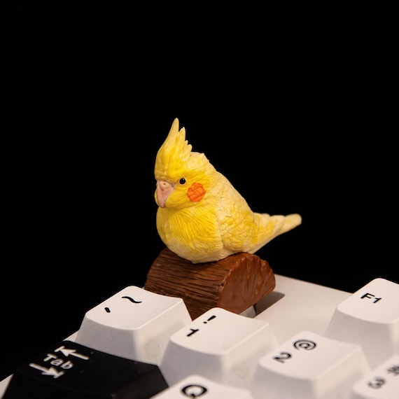 A hand-painted resin cockatiel sculpted as a one-of-a-kind artisan keycap — the kind of tiny wearable desk art that makes keyboard nerds stop mid-scroll.