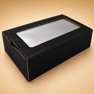 Könnte beinhalten: Eine rechteckige schwarze Schachtel aus Wellpappe mit einem durchsichtigen rechteckigen Sichtfenster im Deckel. Die Schachtel hat eine gerippte Textur auf der gesamten Außenfläche und einen Klappdeckel mit einer kleinen Aussparung zum Öffnen.