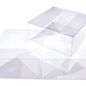 Könnte beinhalten: Ein Set aus durchsichtigen, transparenten Kunststoffboxen. Eine Box ist vollständig zu einer quadratischen Form zusammengebaut, während zwei weitere identische Boxen flach und ungefaltet dargestellt sind, inklusive ihrer Faltkanten.