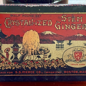 May include: A vintage tin box with a red and gold design featuring a Japanese garden scene. The text on the box reads "Half Pound Net Crystallized Ginger Stem".