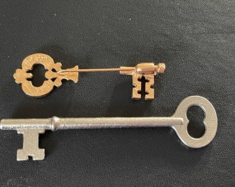 Antique key lot:  Avon gold tone pin and silvertone skeleton-type key