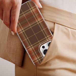May include: A smartphone case featuring a brown, tan, and orange plaid pattern. The case has a rectangular shape with rounded corners and a cutout for the camera lens array, showing the white back of the phone and black camera lenses.