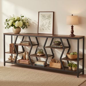May include: A long console table with a dark wood top and a black metal frame featuring geometric zigzag supports. The table has multiple open shelves holding books, a glass cloche with plants, woven baskets, and decorative ceramic items.