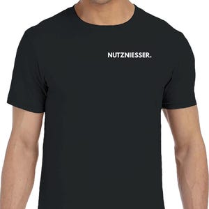 Könnte beinhalten: Ein schwarzes T-Shirt mit kurzen Ärmeln und Rundhalsausschnitt. Das Wort NUTZNIESSER. ist in weißen Großbuchstaben auf der linken oberen Brustseite aufgedruckt. Das Kleidungsstück hat eine Standardpassform mit einem geraden Saum.