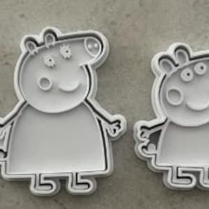 Può includere: Un set di quattro tagliabiscotti in plastica bianca a forma di personaggi di maiale dei cartoni animati. Ogni stampo presenta un contorno in rilievo e dettagli interni per imprimere i tratti del viso, gli arti e gli abiti sull'impasto, disposti in una fila orizzontale.