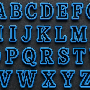 May include: A complete set of twenty-six uppercase alphabet letters from A to Z. Each letter is constructed with a bright blue outer border and a solid black interior, featuring a bold, block-style font design for clear and legible character display.