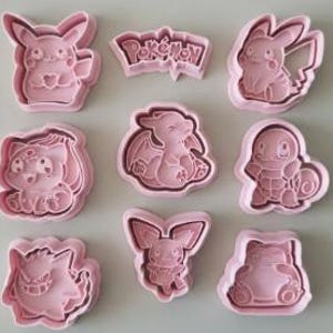 Può includere: Un set di nove tagliabiscotti in plastica rosa chiaro raffiguranti vari personaggi Pokémon e un logo Pokémon. La collezione include forme di Pikachu, Bulbasaur, Charmander, Squirtle, Gengar, Snorlax e altre creature stilizzate.