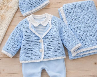 Puede incluir: Un conjunto de bebé de ganchillo en color azul claro que consta de una chaqueta de manga larga con dos botones blancos, un gorro a juego con borde blanco, un pantalón azul claro liso y una manta de ganchillo azul claro con borde blanco.
