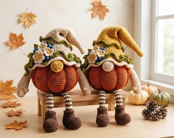 May include: Two crocheted pumpkin gnomes with dangling legs, wearing floppy hats adorned with small white flowers and blue berries. The gnomes feature orange pumpkin bodies, striped legs, and brown boots, sitting on a small wooden bench.
