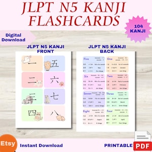 May include: A set of JLPT N5 Kanji flashcards featuring 104 characters. The front side displays individual Kanji characters on pastel-colored backgrounds with small cat illustrations. The back side provides English translations, readings, and meanings for each Kanji.