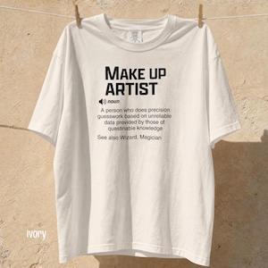 Könnte beinhalten: Ein elfenbeinfarbenes Kurzarm-T-Shirt mit schwarzem Textaufdruck: MAKE UP ARTIST, noun, A person who does precision guesswork based on unreliable data provided by those of questionable knowledge, See also: Wizard, Magician.