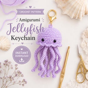 May include: A light purple crocheted jellyfish keychain with black safety eyes and a gold-toned metal lobster clasp. The text on the image reads CROCHET PATTERN Amigurumi Jellyfish Keychain INSTANT DOWNLOAD, accompanied by yarn, a hook, and scissors.