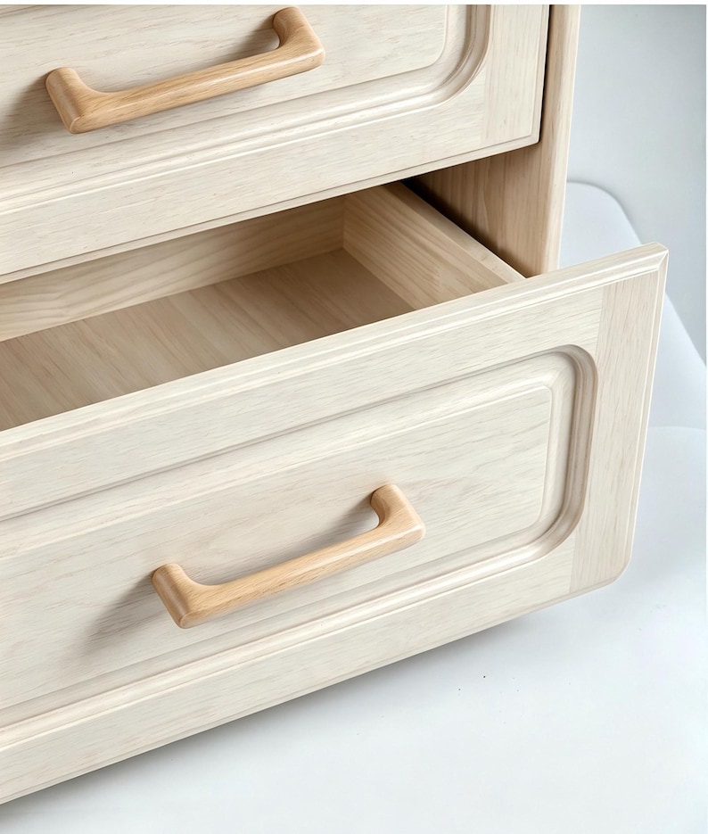 Peut inclure: Une commode en bois clair dot&eacute;e de deux tiroirs aux bords arrondis et lisses avec un design &agrave; panneau encastr&eacute;. Chaque tiroir est &eacute;quip&eacute; d'une poign&eacute;e incurv&eacute;e en bois naturel qui s'harmonise avec le grain clair des fa&ccedil;ades.