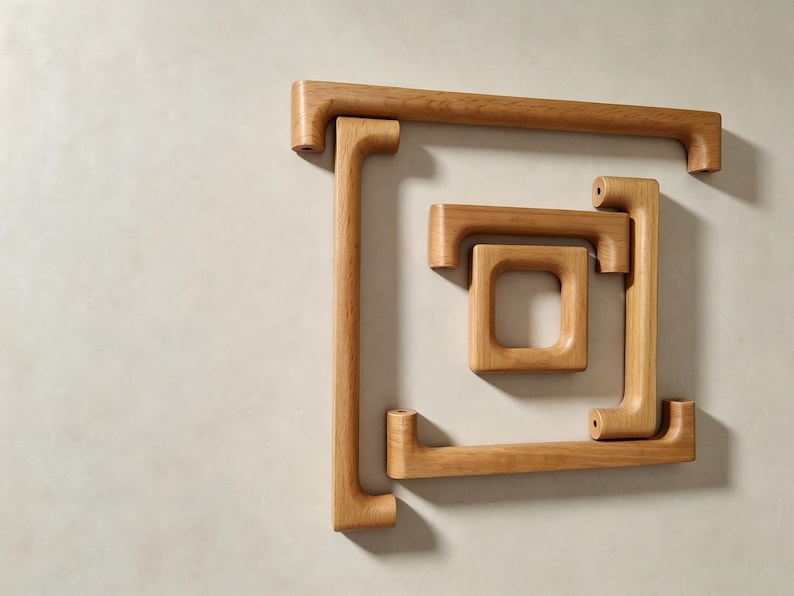 Peut inclure: Un ensemble de poign&eacute;es de placard en bois brun clair dispos&eacute;es en carr&eacute; imbriqu&eacute;. Le lot comprend quatre pi&egrave;ces distinctes aux bords arrondis et lisses avec un grain de bois visible, pr&eacute;sentant des trous pr&eacute;-perc&eacute;s pour la fixation.