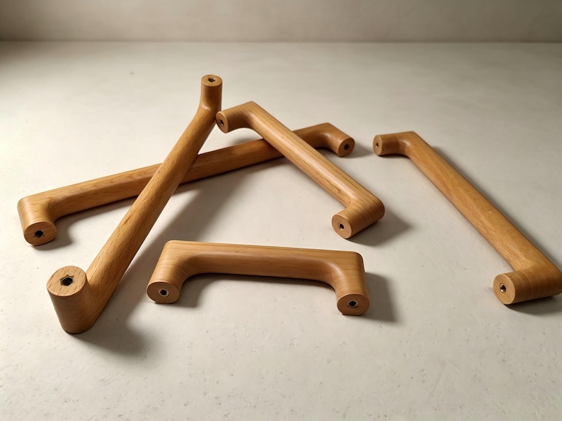 Peut inclure: Un ensemble de quatre poign&eacute;es de placard en bois brun clair au design cylindrique et lisse. Chaque poign&eacute;e pr&eacute;sente deux points de fixation circulaires aux extr&eacute;mit&eacute;s, avec des trous de vis m&eacute;talliques visibles au centre des faces plates.