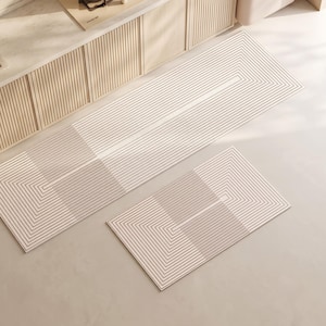 May include: A set of two rectangular floor mats featuring a cream-colored base with a repeating pattern of thin, dark brown concentric lines that form geometric shapes across the surface, creating a linear and structured visual design.
