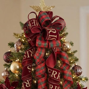 May include: A Christmas tree topper featuring a large, multi-looped bow made of red velvet and green plaid ribbon with the gold text Merry Christmas printed on the velvet sections, topped with a glittery gold star and cascading ribbon tails.