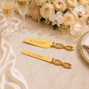 Puede incluir: Un juego de cuchillo y pala para pastel en tono dorado con un diseño de mango en forma de infinito. Las hojas están grabadas con el texto 'Monroe & Matthew' y '12-07-2025' junto a un pequeño icono de dos copas de champán brindando.