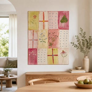 Peut inclure: Une tenture murale rectangulaire présentant un motif patchwork composé de douze panneaux distincts. Chaque panneau affiche des illustrations botaniques peintes à la main, des croix géométriques ou des motifs floraux dans des tons jaune, rose et rouge.